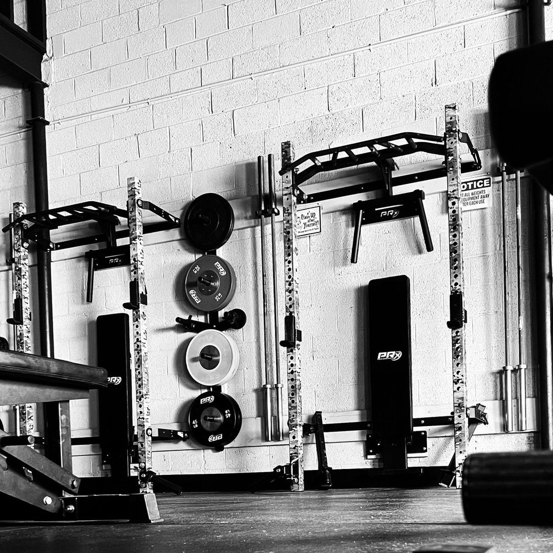 Founders Gym squat racks and weight plates in a black and white fitness facility photo