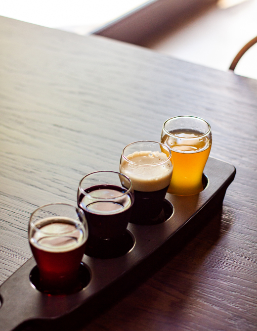  Beer flight with four sample glasses of craft beer on a wooden table