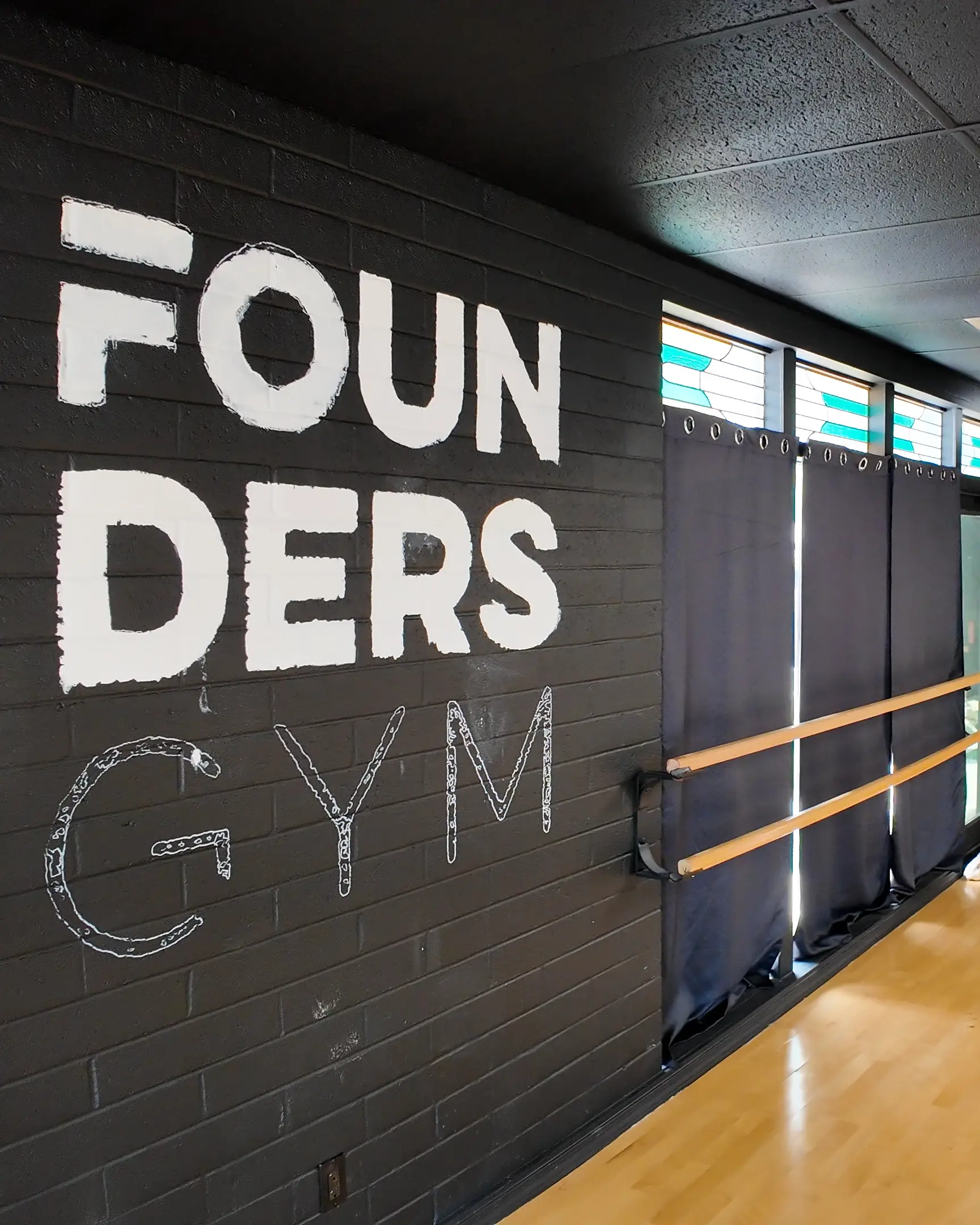 Founders Gym squat racks and weight plates in a black and white fitness facility photo