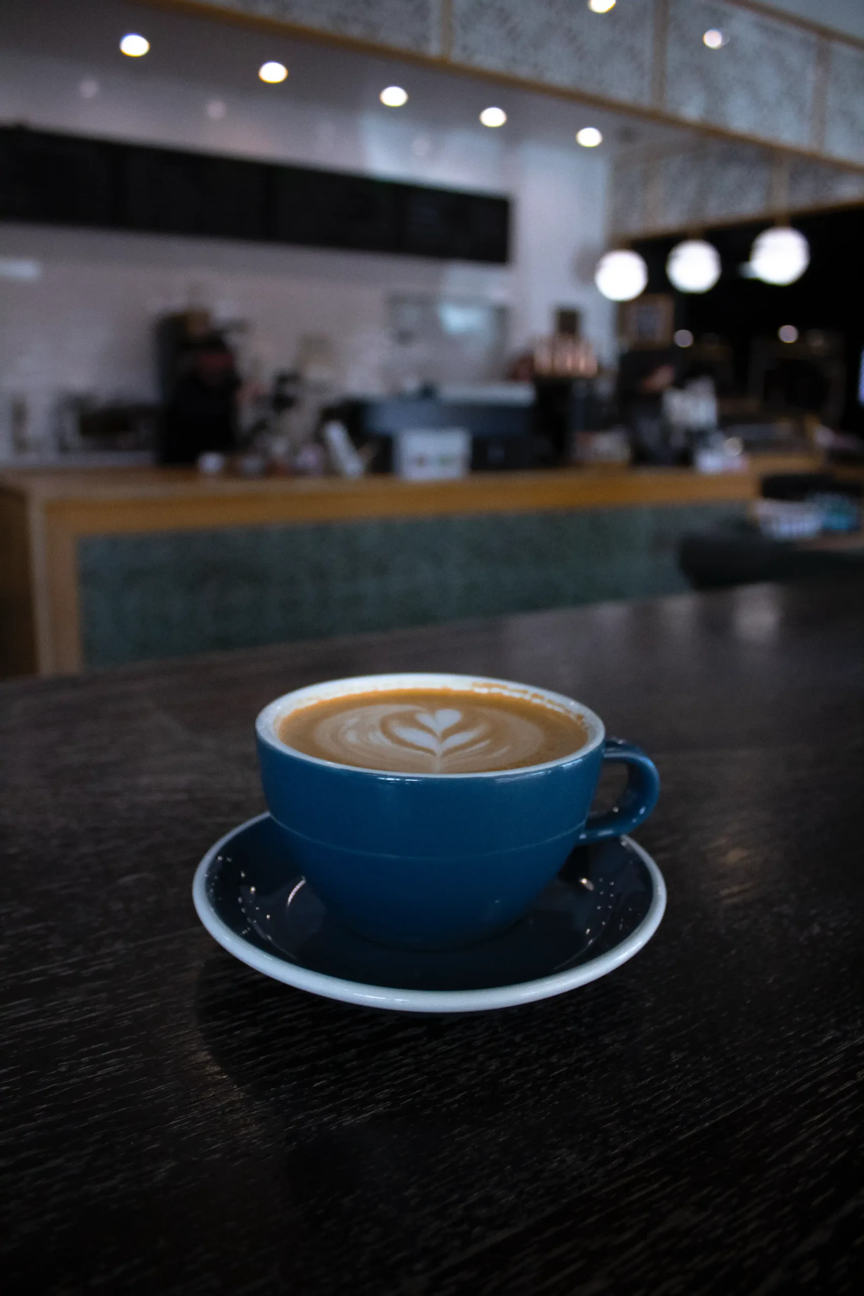 Merchant Coffee In Prescott Az Latte with heart-shaped art in a blue cup on a table at Merchant Coffee Co.
