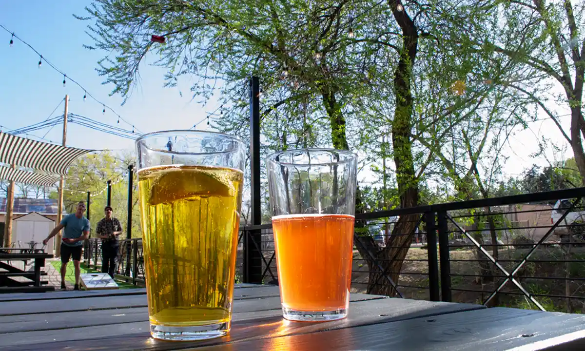 Two pints of beer on the Founding Fathers Collective patio in Prescott with string lights and cornhole—best bars in Prescott.